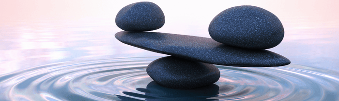 Two rocks perfectly balanced on another rock acting like a scale over the water